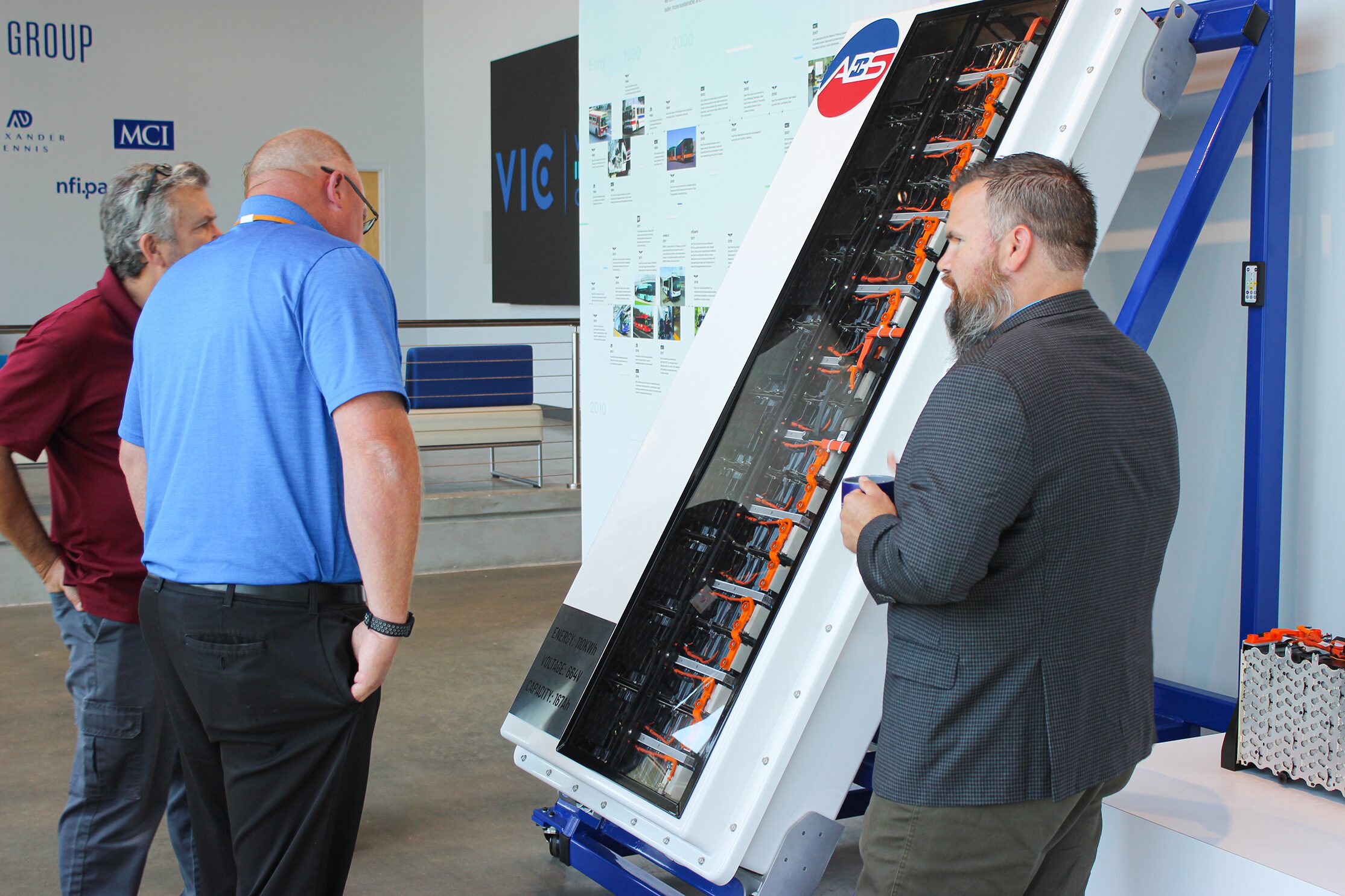 Visitors touring the MCI Vehicle Innovation Center, exploring motorcoach features and technology while interacting with vehicle displays and product experts. The image highlights customer engagement, hands-on learning, and opportunities to experience MCI's latest innovations and transportation solutions firsthand.